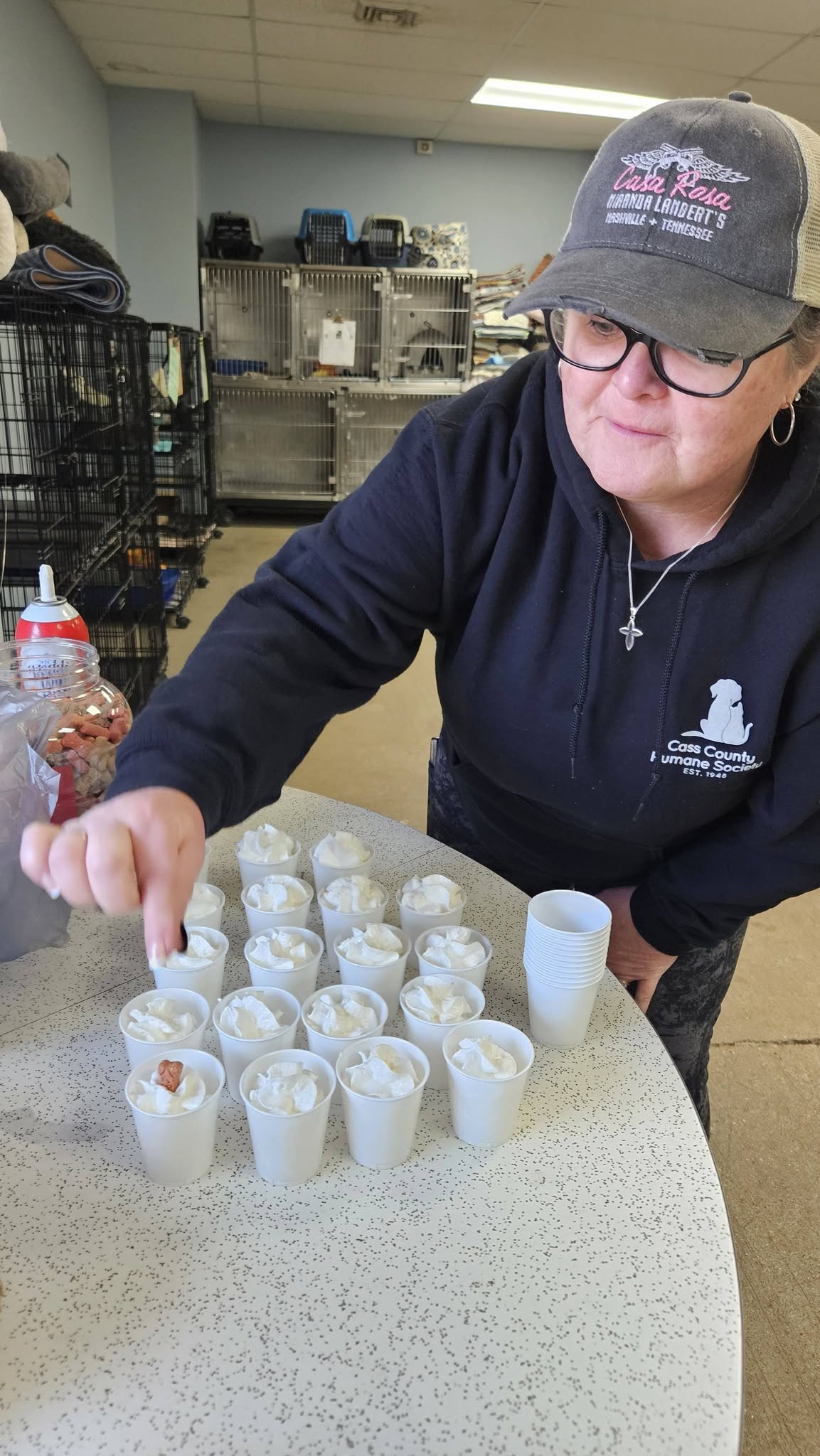 A volunteer preparing pup cups — whipped cream treats for shelter dogs